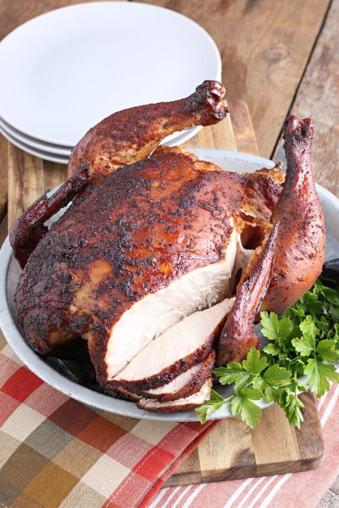 Poulet fumé en canette de bière servi avec une serviette à carreaux orange et brun